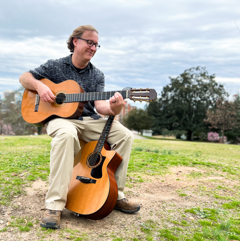 man sitting on cajon holding guitar - Bobby Hall
