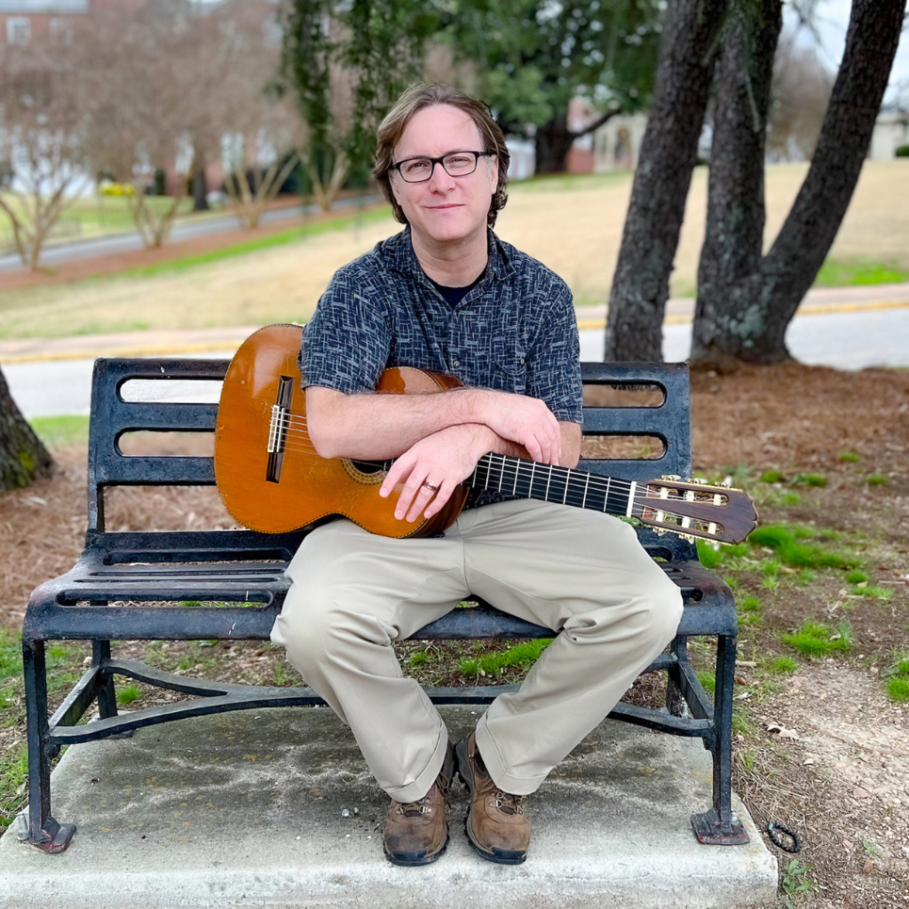 Bobby Hall - guitarist sitting on bench with guitar